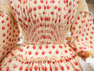 Close-up on the cinched, shirred waist on a dress which has a cream background decorated in a pink diamond-shaped repeat pattern
