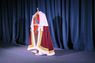A red, black and gold regimental uniform, presented on a stand, and with a regal red, white and gold cape on top